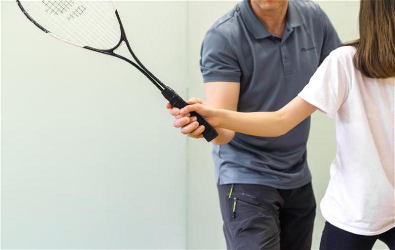 Man teaching a kid how to swing a squash racket