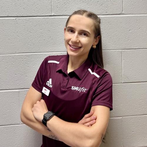 A young female personal trainer leaning against a wall