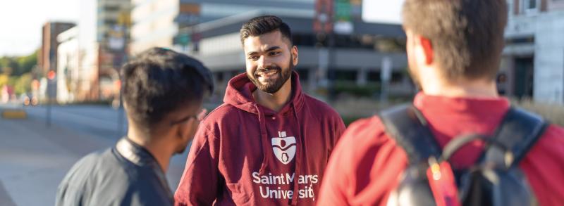 Student wearing university branded clothing while socializing with his fellow classmates