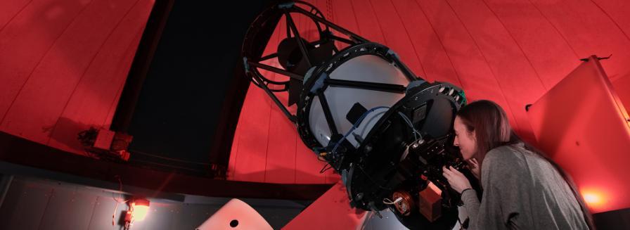 A person looks into a large telescope.