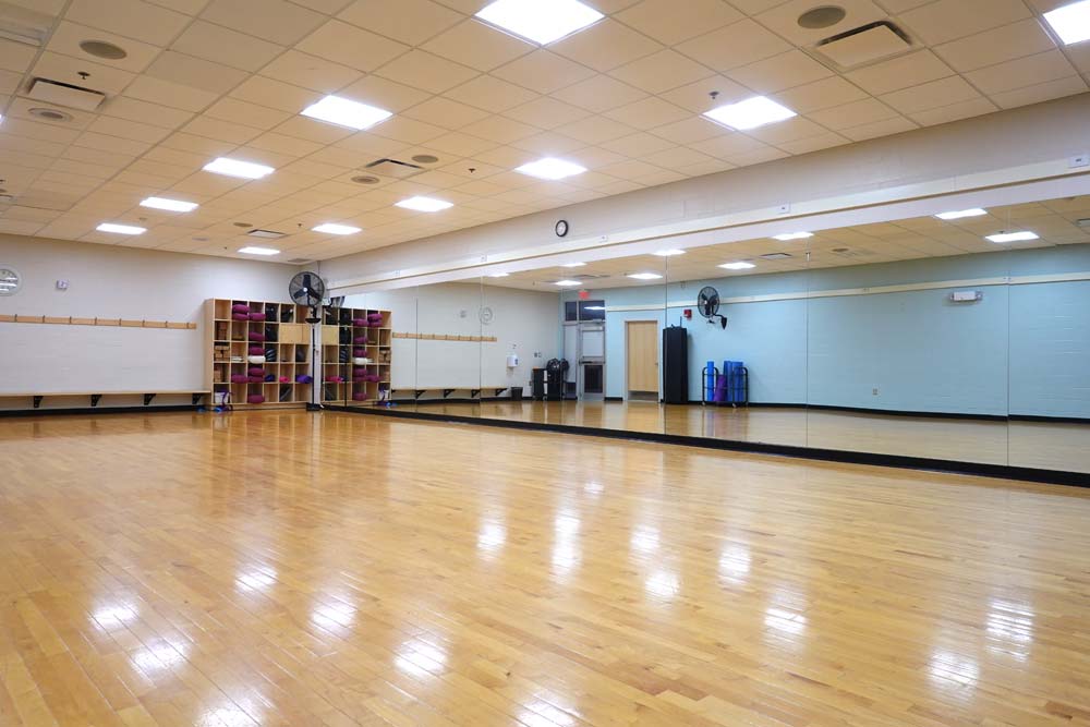 Studio A. Dance style studio with hardwood floo and mirrored wall.