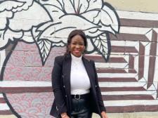 Black Student Advisor smiling, standing in front of floral wall mural