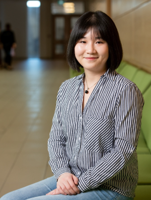 A student posing for a picture inside, in a long hallway