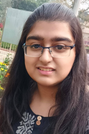 A student standing outside, wearing glasses